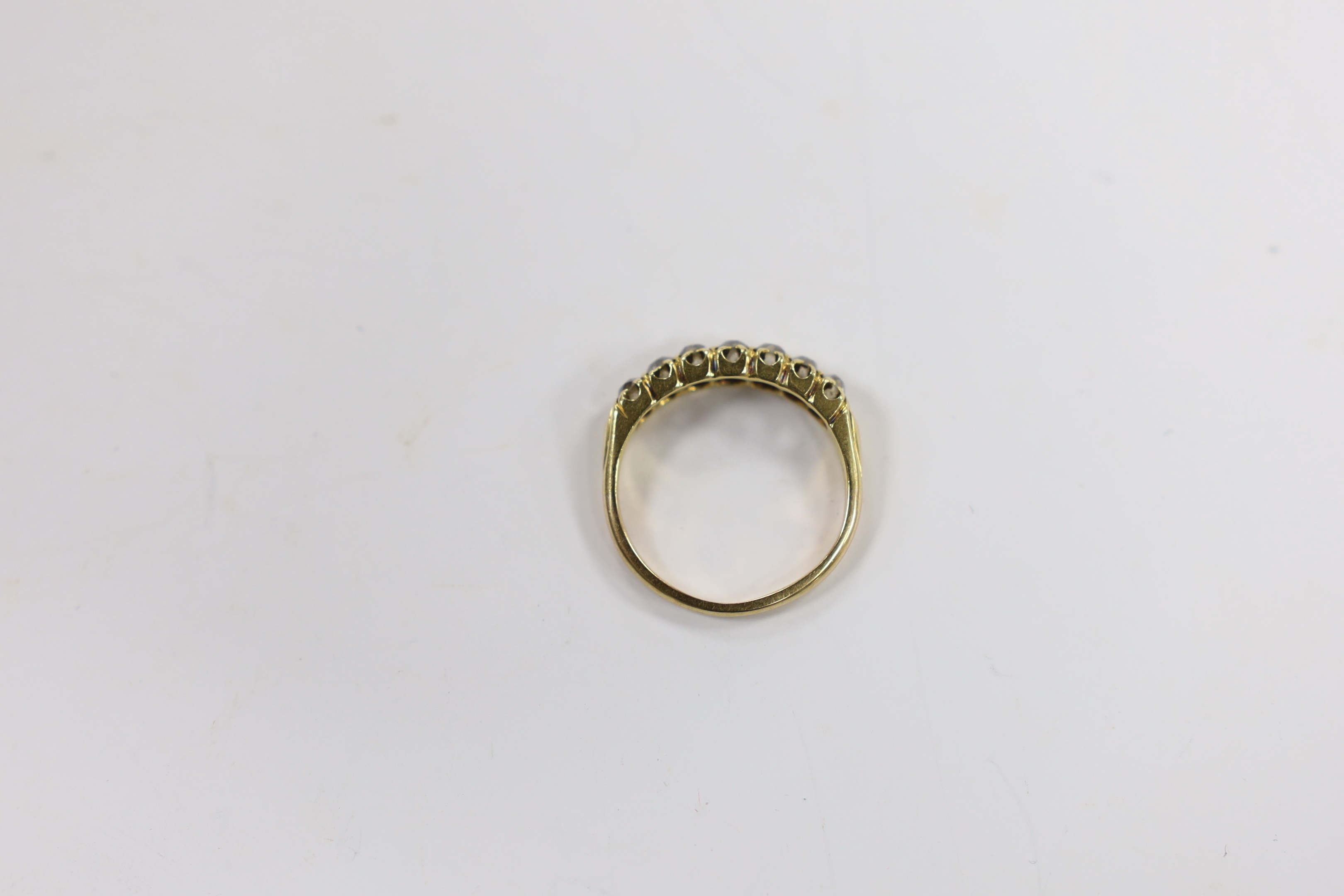 A yellow metal and seven stone diamond set half hoop ring, size N/O, gross weight 3.1 grams.